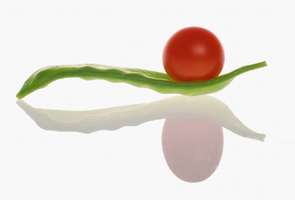 A cherry tomatoe on snow pea with reflection